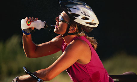 Woman cyclist indulging in water during warm ride.